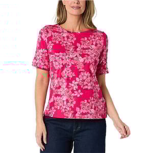 A woman wearing a pink floral-patterned short-sleeve shirt paired with dark jeans.