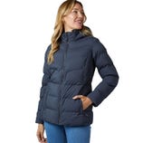 A woman is wearing a puffer jacket with a hood, styled in a dark color, paired with light blue jeans.