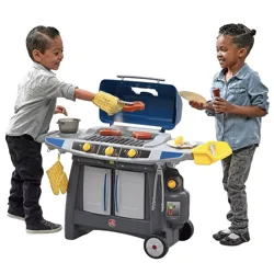 Two children play with a toy grill set, featuring realistic details like grill covers, knobs, and pretend food items such as hot dogs and corn. The set includes accessories like oven mitts and tongs.