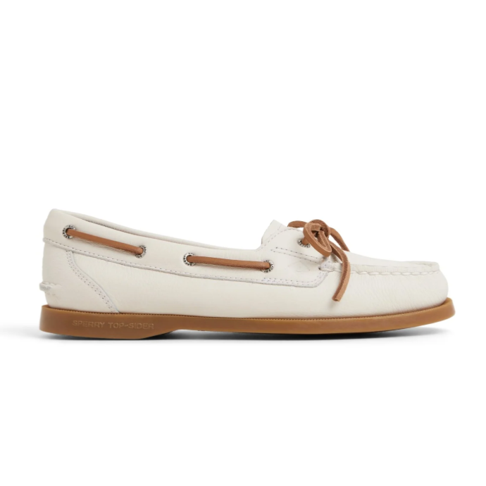 A white leather boat shoe with tan laces and a brown rubber sole, featuring the \“SPERRY TOP-SIDER\“ branding on the side of the sole.