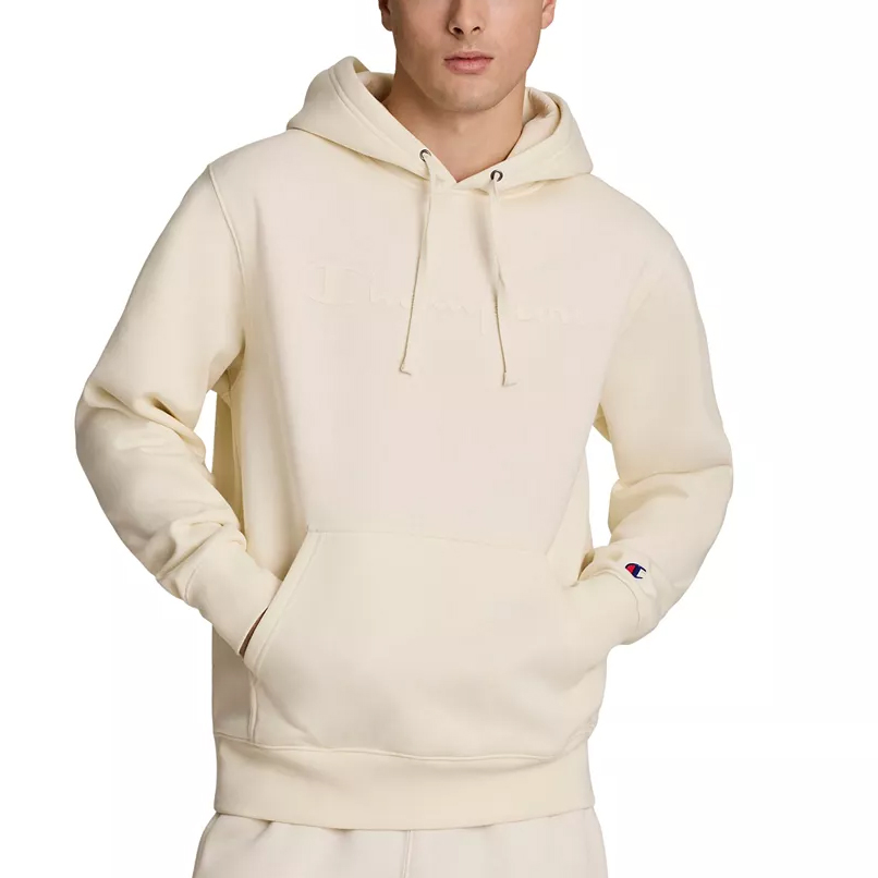 A person is wearing a cream-colored hoodie with a drawstring hood and kangaroo pocket. The small Champion logo is visible on the sleeve.