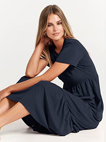 A woman is seated, wearing a navy blue maxi dress with short sleeves and a gathered waist.
