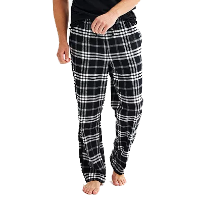 A person is wearing black and white plaid pajama pants with an elastic waistband and a relaxed fit, paired with a black shirt.