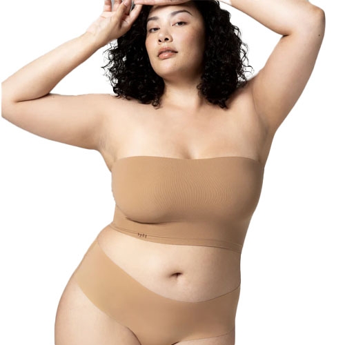 A woman is wearing a strapless bandeau bra and matching seamless underwear in a nude color.