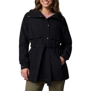 A woman is wearing a black, belted rain jacket with a hood and snap buttons over a pink top and khaki pants.