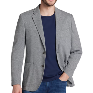 A man wearing a light gray blazer over a navy T-shirt, paired with blue jeans.