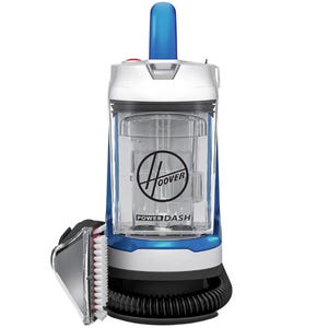 A Hoover PowerDash portable carpet cleaner with a transparent water tank, blue handle, and an attached hose featuring a cleaning brush.