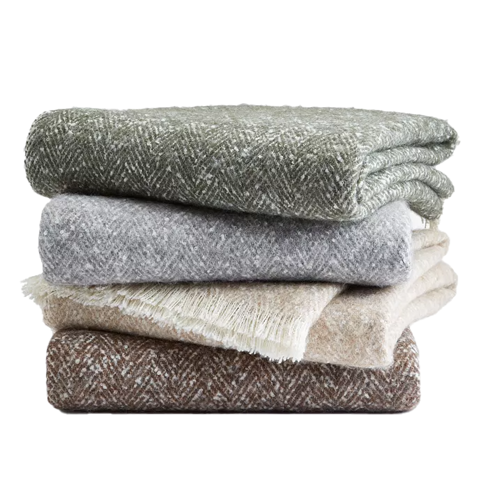 Stack of four Hotel Collection Herringbone Throws in shades of green, gray, beige, and brown, featuring a subtle woven pattern and soft texture.