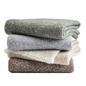 Stack of four Hotel Collection Herringbone Throws in shades of green, gray, beige, and brown, featuring a subtle woven pattern and soft texture.