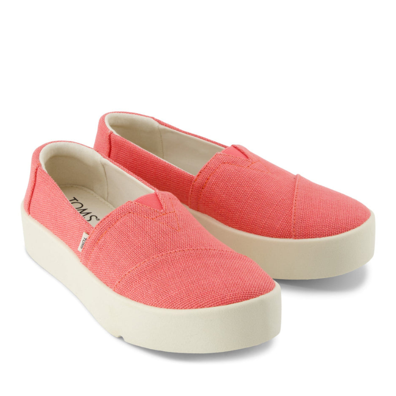 Pair of coral-colored slip-on shoes with a white platform sole and a subtle branding label on the side.