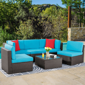 Outdoor sectional set with blue cushions and red pillows, featuring a glass-top coffee table, situated on a geometric outdoor rug by a pool.