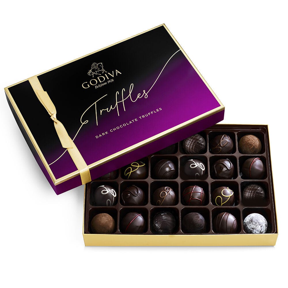 Godiva dark chocolate truffles in a purple and black box with a yellow ribbon, featuring an assortment of varied designs and textures.
