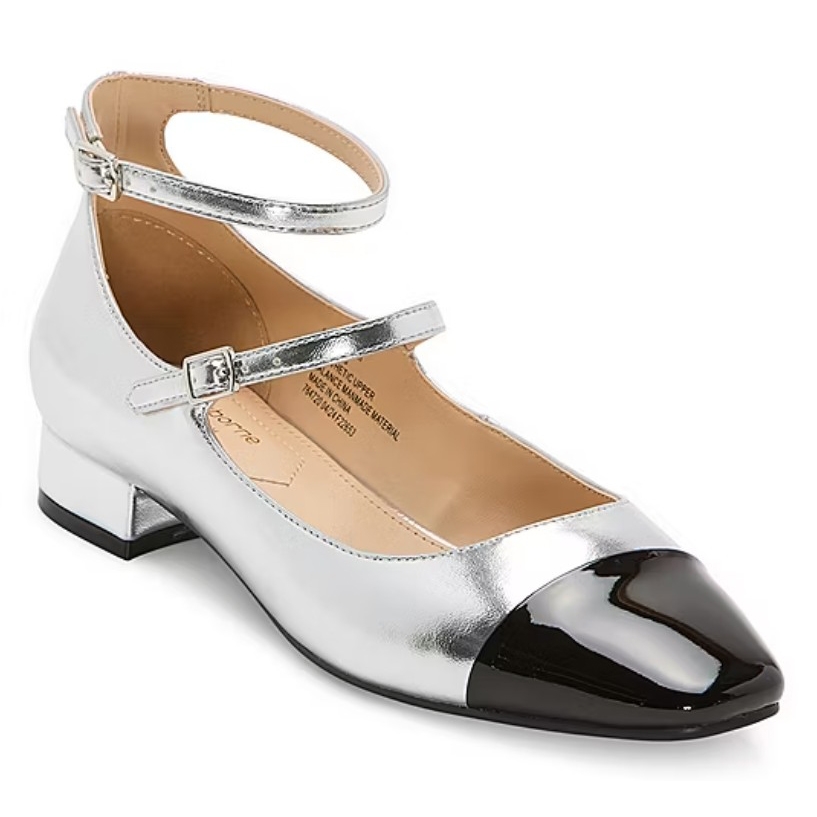 Silver ballet flat with a black patent cap toe, featuring a low block heel and two ankle straps with buckles.