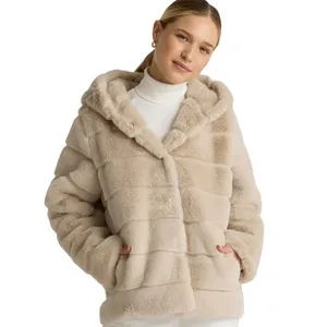 A woman is wearing a light beige faux fur hooded jacket with horizontal stripe patterns over a white turtleneck sweater.