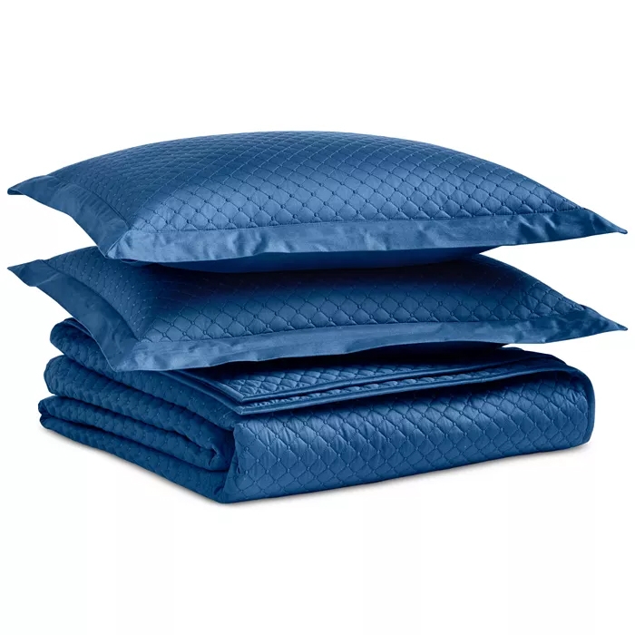A set of two blue quilted pillows and a matching quilted blanket with a subtle geometric pattern.