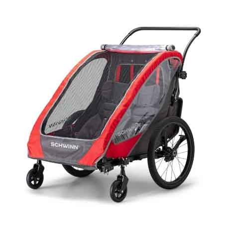 Schwinn Summit Double Bike Trailer is a child carrier with a red and gray design, featuring a protective mesh cover, two seats, and a handlebar for easy maneuvering. It has two large rear wheels and two smaller front wheels for stability.