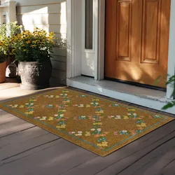 A decorative doormat with a floral pattern lies at the entrance of a wooden door. A large pot of yellow flowers is to the side, enhancing the welcoming appearance of the porch area.