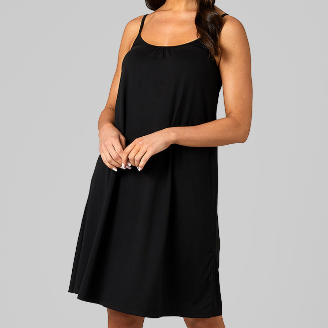 A woman is wearing a sleeveless black dress with a flowy silhouette and a round neckline, designed for a relaxed and comfortable fit.