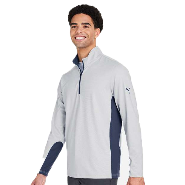 A man wears a light gray long-sleeve quarter-zip pullover with navy side panels and a Puma logo on the sleeve.