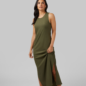 A woman is wearing a sleeveless, olive green, mid-length dress with a side slit.
