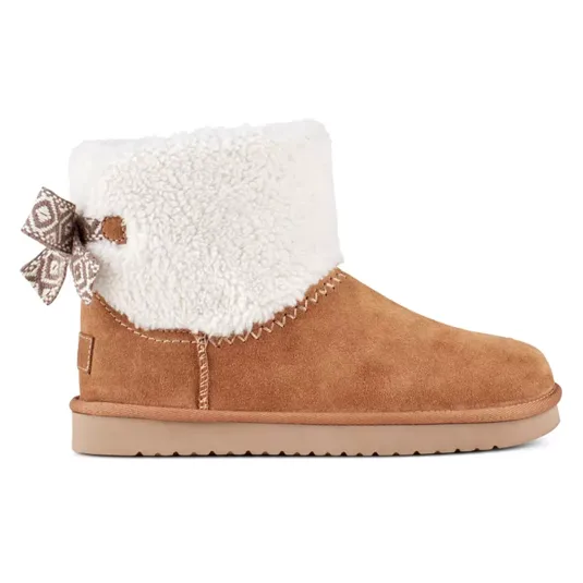 Tan suede ankle boot with white faux fur lining, featuring a patterned bow on the side and a flat sole.