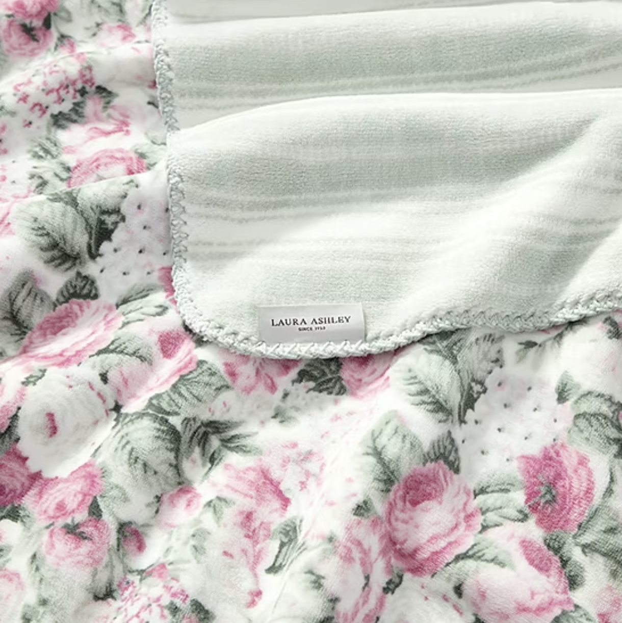 Floral-patterned fabric with pink roses, featuring a soft gray and white lining, labeled \“Laura Ashley Since 1953.\“