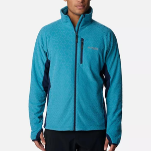 A man wearing a light blue, patterned, zip-up jacket with a high collar and a dark sleeve panel.