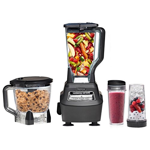 A Ninja kitchen system featuring a blender with a tall jar filled with fruits, a food processor with cookie dough, and two blending cups showing a smoothie and berries with ice.