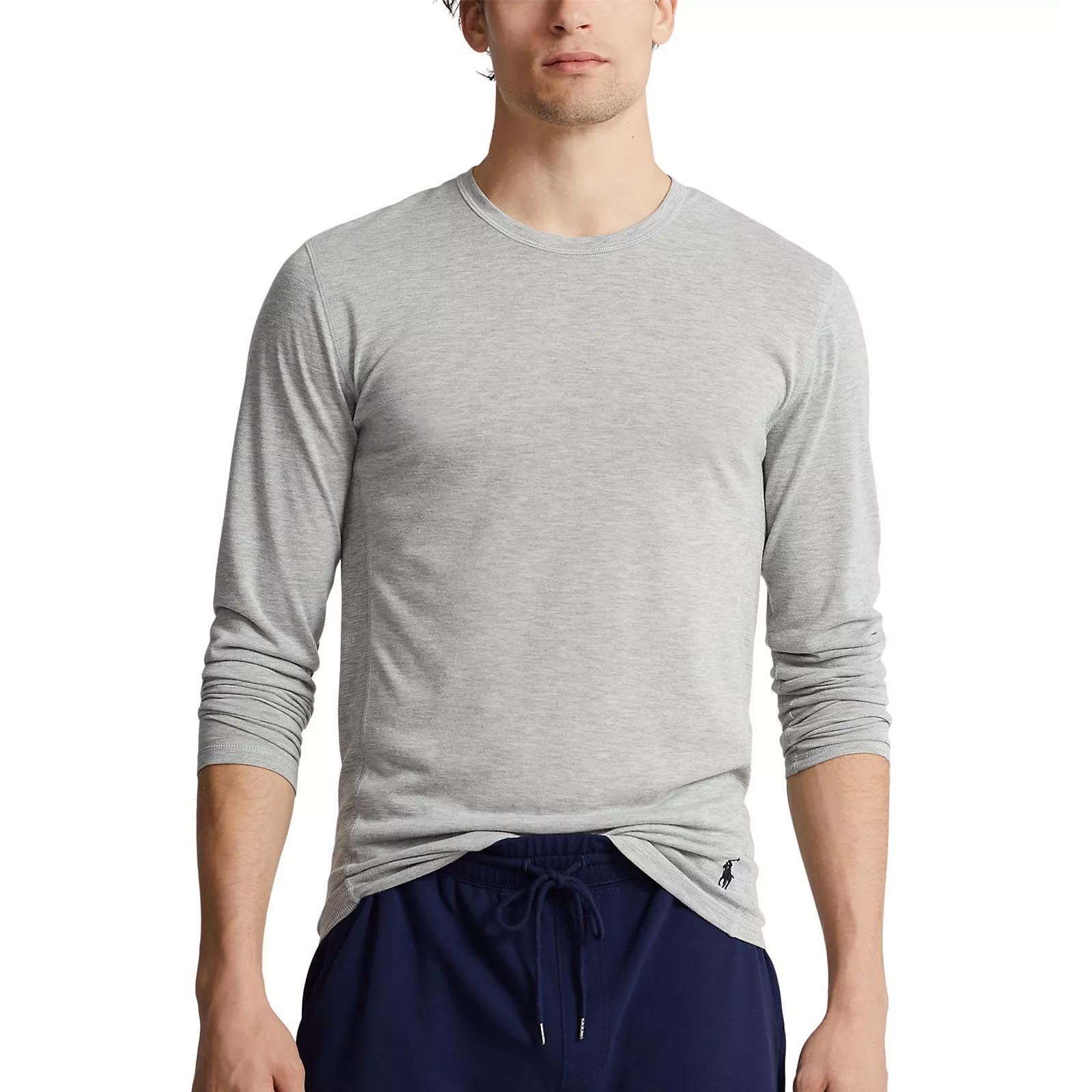 A person is wearing a light gray long-sleeve shirt with a small logo near the hem and navy blue drawstring pants.
