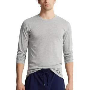 A person is wearing a light gray long-sleeve shirt with a small logo near the hem and navy blue drawstring pants.