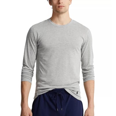 A person is wearing a light gray long-sleeve shirt with a small logo near the hem and navy blue drawstring pants.