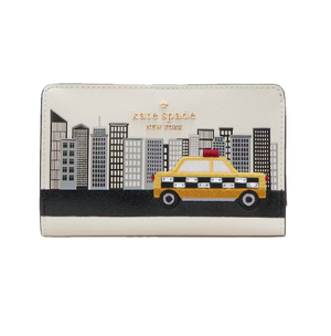 A Kate Spade New York wallet featuring a cityscape with high-rise buildings and a yellow taxi embellishment against a cream background.