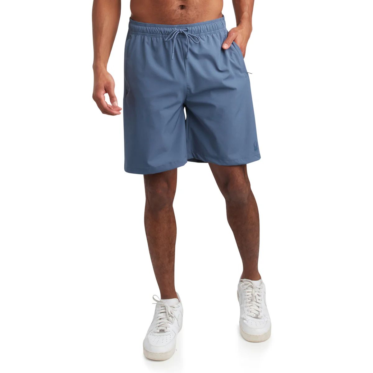 A person wearing blue athletic shorts with an elastic waistband and drawstring, paired with white sneakers.