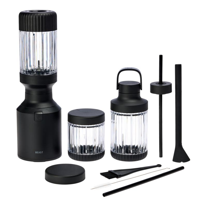 The Beast Mini Blender Bundle includes a sleek black blender base, two clear blending containers with black lids, a cleaning brush, a straw, and a tamper tool. The set is designed for compact and efficient blending, with a modern aesthetic.