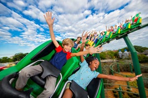 A roller coaster ride with excited children raising their hands is depicted, representing an attraction at Legoland California.