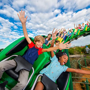 A roller coaster ride with excited children raising their hands is depicted, representing an attraction at Legoland California.