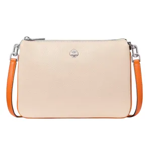 A beige leather crossbody bag with a silver spade logo and orange strap accents.