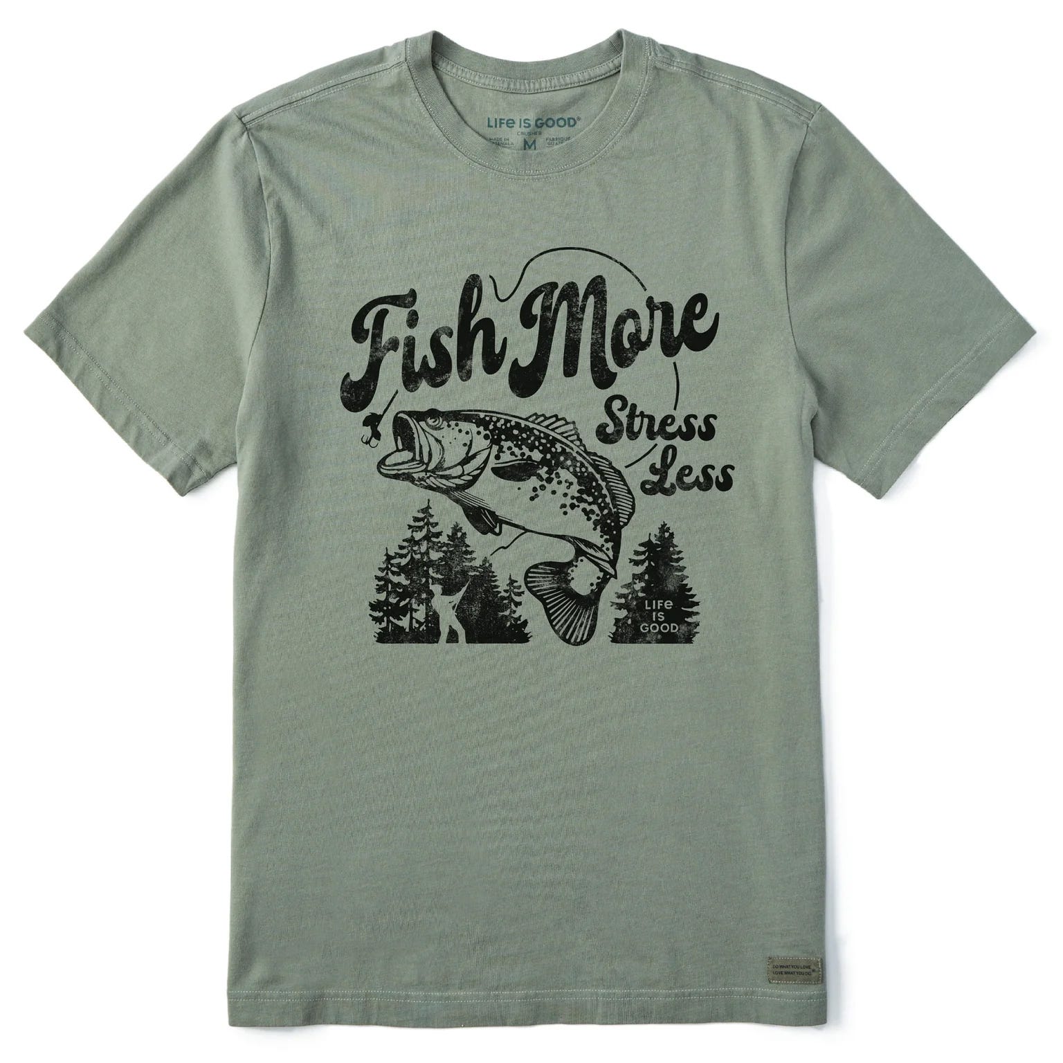Olive green T-shirt featuring a design with a large fish, trees, and the phrase \“Fish More Stress Less\“ in black print.