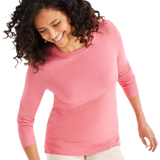 A person is wearing a pink, long-sleeve crew neck sweater with a relaxed fit and curved hem. The sweater is paired with light-colored pants.