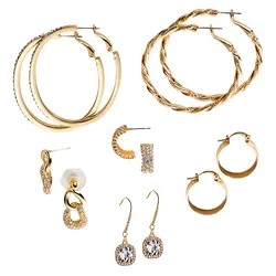 A set of gold-toned earrings featuring two pairs of large hoop earrings, a twisted rope design, and a thick smooth design. Includes smaller hoops, crystal-accented studs, and a pair of dangle earrings with clear gemstones.