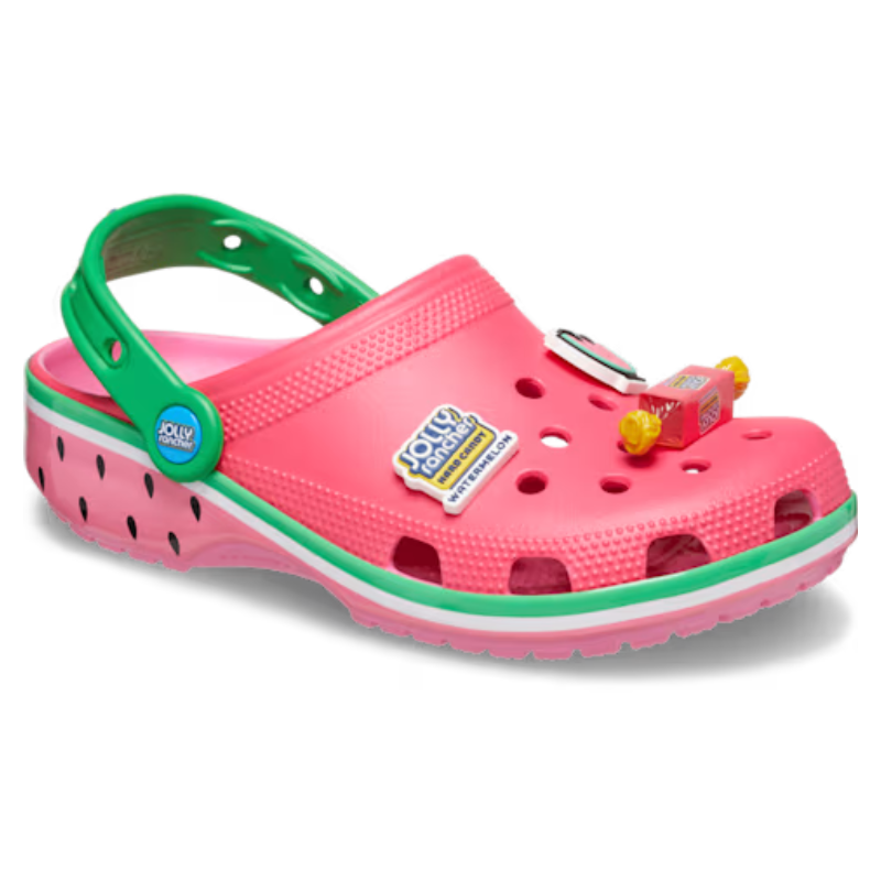 A pink and green Crocs clog themed around Jolly Rancher watermelon flavor, featuring candy-themed charms and ventilation holes.