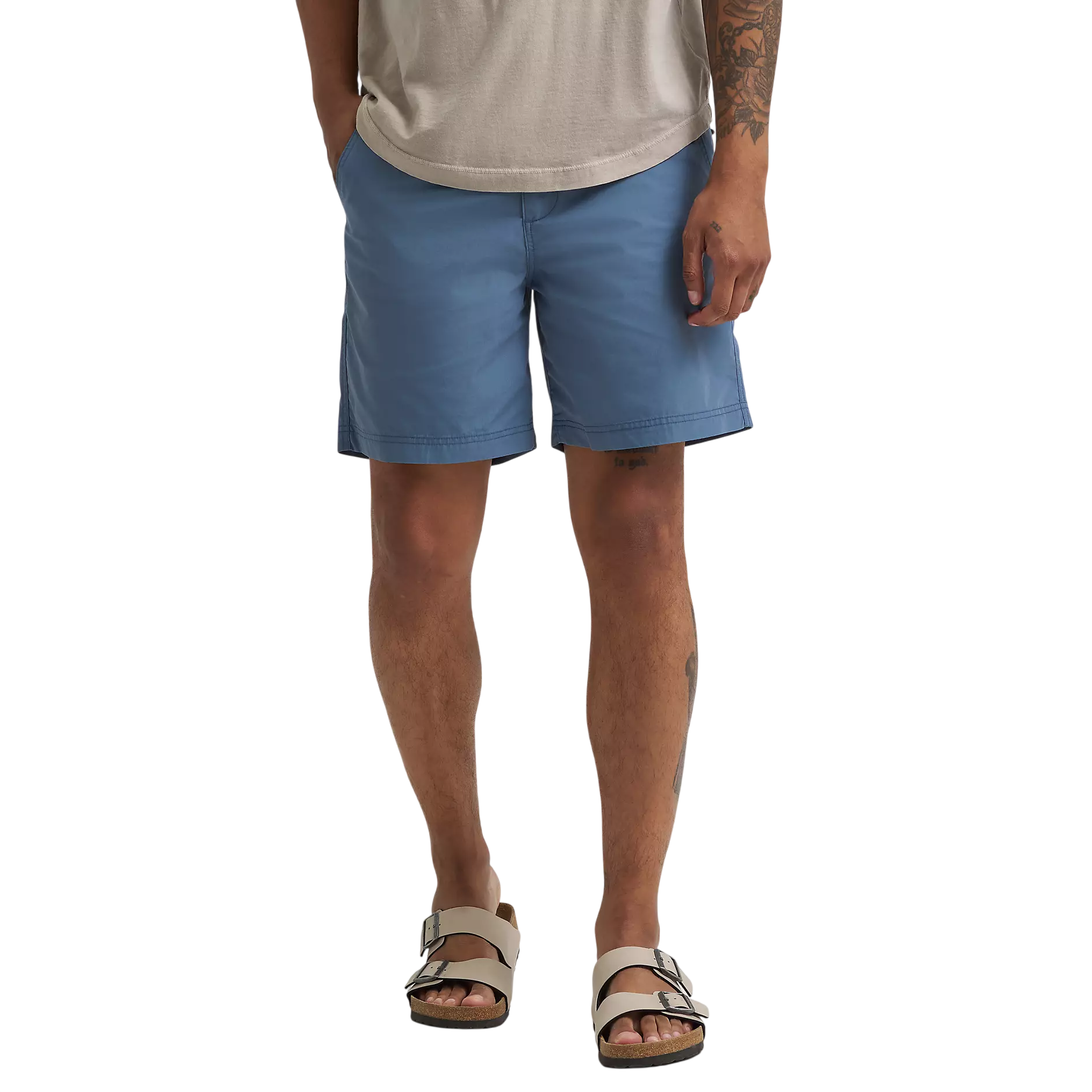 A person is wearing blue shorts paired with beige double-strap sandals, complemented by a neutral-colored t-shirt.