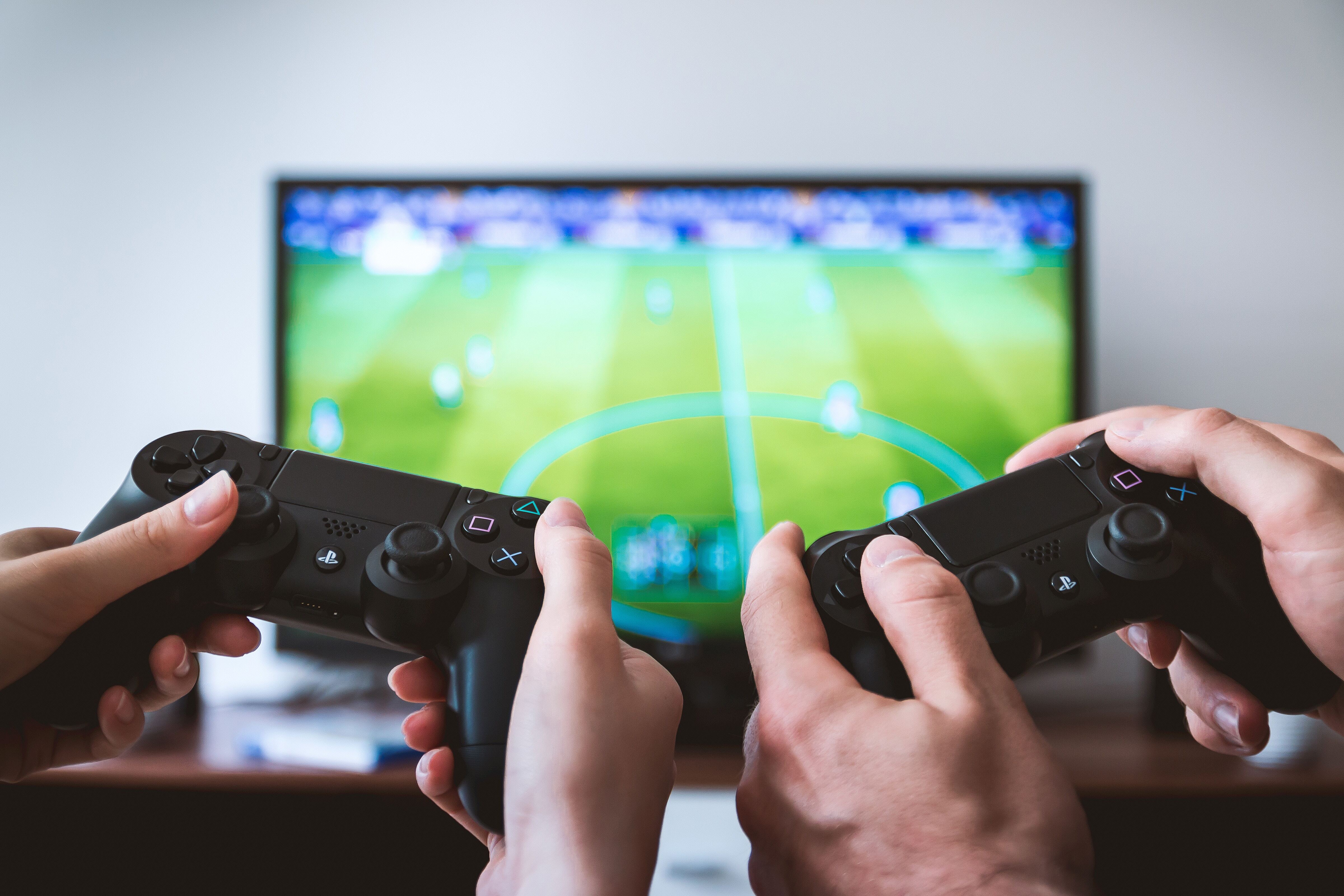 Two people holding gaming controllers in front of a television displaying a soccer game.