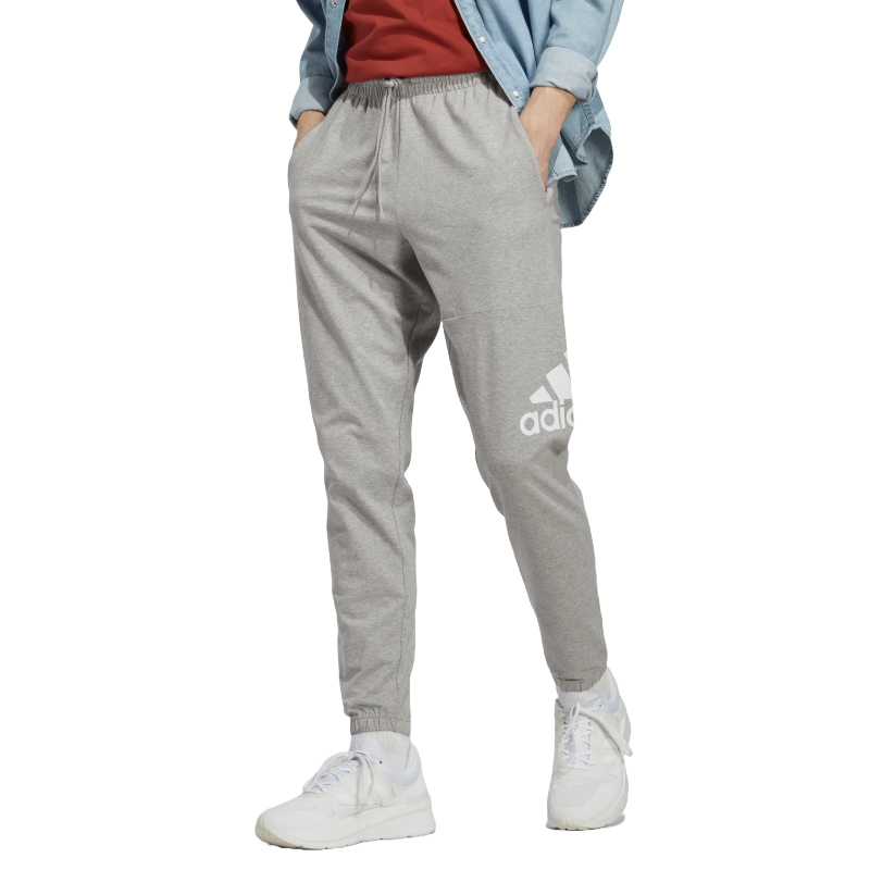Gray Adidas sweatpants with a large white logo on the left leg, paired with white sneakers, a red shirt, and a light blue denim jacket.