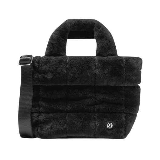 Black furry tote bag with a shoulder strap and a small logo on the front.