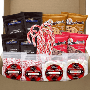 A gift set with Ghirardelli hot cocoa mix packets, Grandma's brand cookies, candy canes, and peppermint bark candies, presented in an open box.