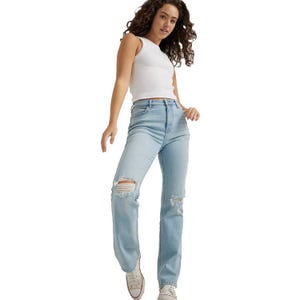 High-rise, light blue Wrangler jeans with a straight leg, distressed detailing on the knees, worn with a white tank top and white sneakers.