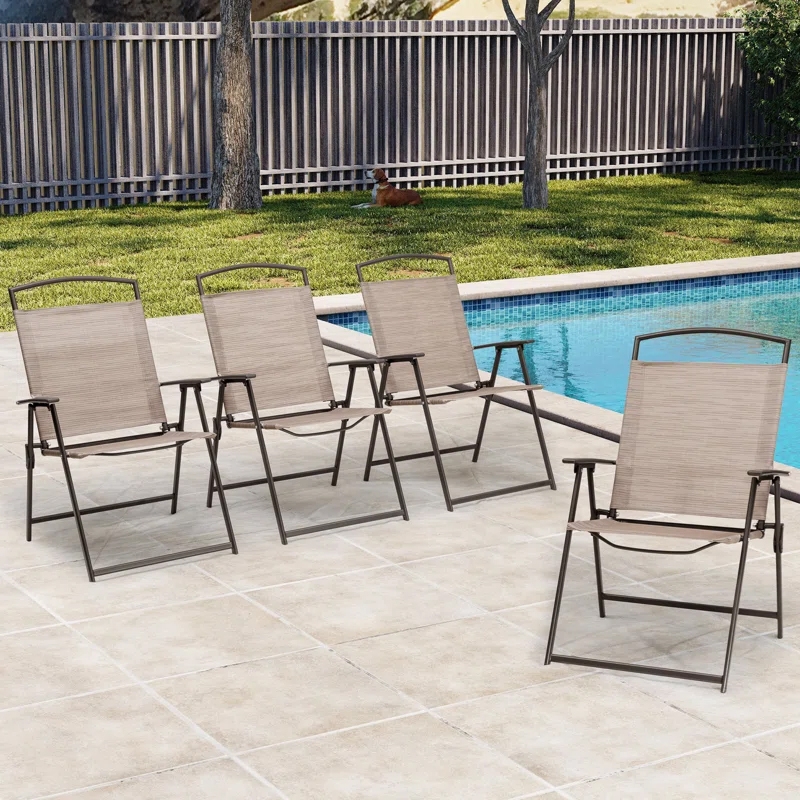 Four outdoor folding armchairs with metal frames and beige-textured sling seats are arranged on a patio by a pool. Each chair features armrests and a simple, modern design.