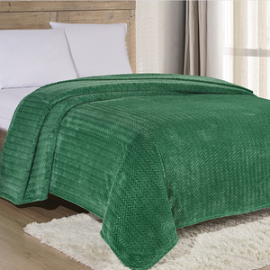 A green textured bedspread covers a bed with white pillows, set on a wooden floor with a light-colored rug nearby.