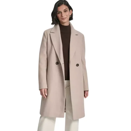 A woman is wearing a long beige coat with two buttons over a brown turtleneck sweater, paired with cream-colored wide-leg pants and dark ankle boots.